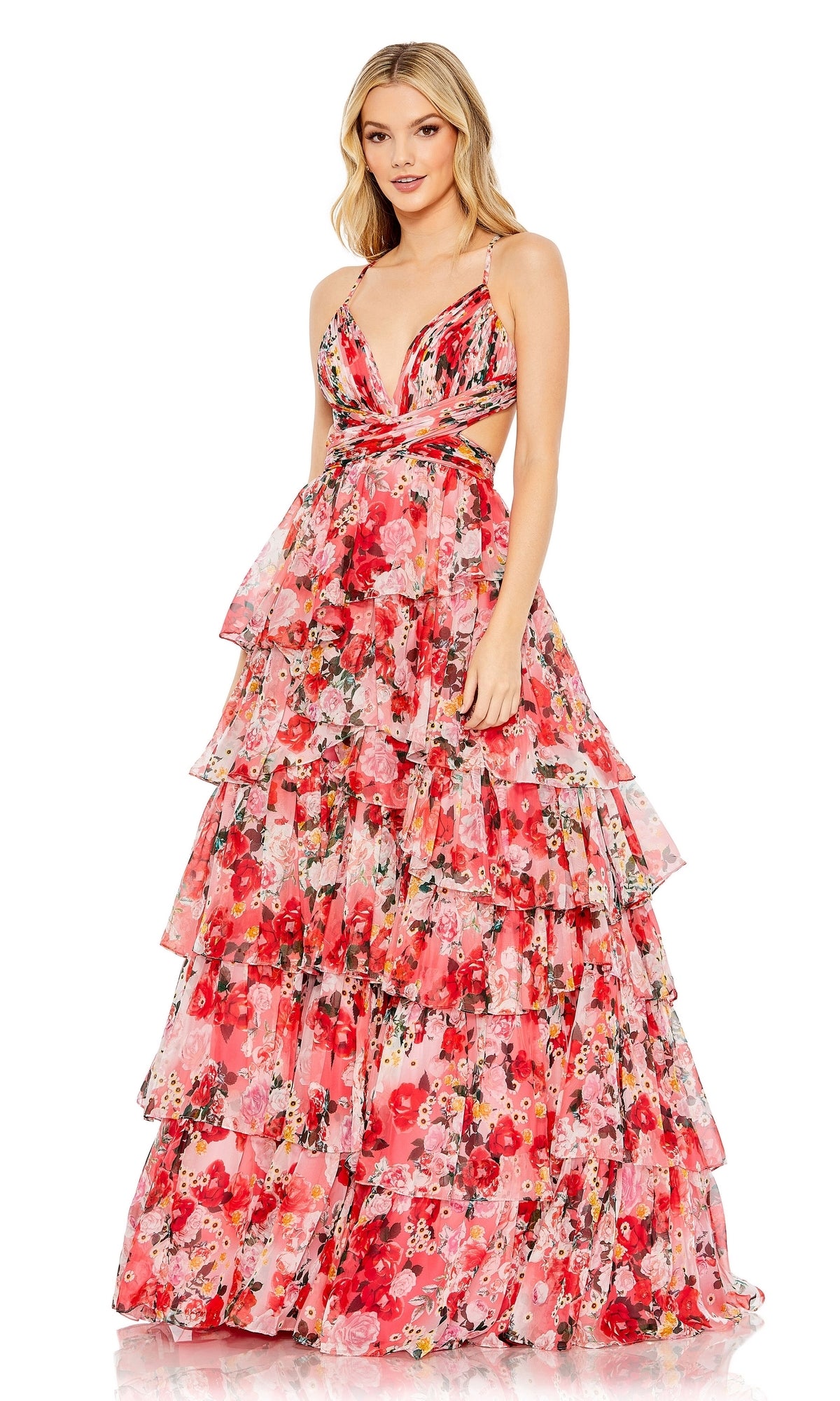 A woman stands facing forward in the Mac Duggal 67985 Pink Print Ruffled Formal Dress, featuring a sleeveless floral design with a deep V-neck, cutout sides, and a multi-tiered ruffled evening gown silhouette.